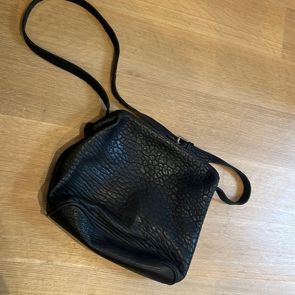 Edition Paris black pebble leather snap-close crossbody bag.